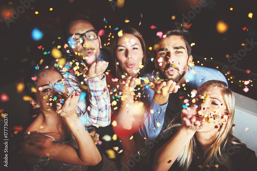 Photographie Group of people having a party, blowing confetti