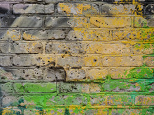 Old Brick Wall With Yellow And Green Paint Traces