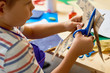 © Seventyfour - Portrait of cute little boy  cutting paper in arts and crafts class of pre-school making handmade gift