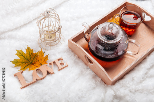 Zdjęcie XXL jesienna scena domowa w skandynawskim stylu. Ciepły sweter z dzianiny, świece, kubek ciepłej herbaty i inne dekoracje na tacy w łóżku.