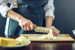 © Artem - The chef in black apron cuts with a knife mozzarella cheese for pizza. Concept of eco-friendly products for cooking