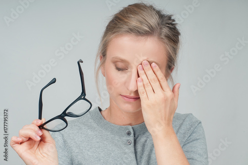 Fotografie, Obraz Tired woman with eyeglasses, covering eye with hands