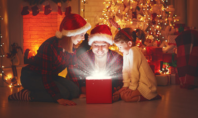 Merry Christmas! happy family mother father and child with magic gift near tree