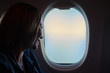 Young beautiful woman looking into the airplane window