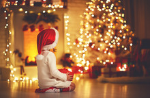 Child Girl  Sitting  Back In Front Of  Christmas Tree On Christmas Eve