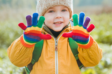 Portrait of cute little boy in a yellow jacket and bright gloves.