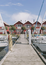 Wooden Dock With Yachts Leading To Red Summer Houses