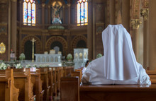 The Nun Sits In The Church And Prays To God. A Nun In Traditional White Robes Meditates In A Christian Cathedral. Prayer To Jesus.