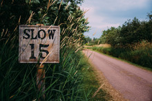 Wooden Sign Showing Slow Fifteen Speed Limit By A Countryside Road