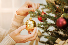 Close Up Of Woman Decorating Tree For Christmas