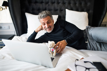 Wall Mural - Mature businessman with laptop in a hotel room.