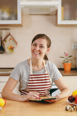 A young beautiful woman looking for a recipe in the tablet in the kitchen. Vegetable salad. Dieting concept. Healthy lifestyle. Cooking at home. Prepare food.