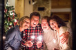 © Halfpoint - Senior friends with sparklers next to Christmas tree having fun.