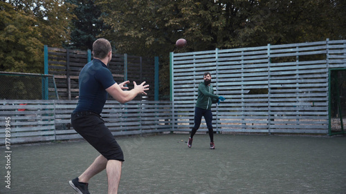 Obraz na płótnie Dwóch kolegów ćwiczy piłkę przejeżdżającą na polu podczas gry w futbol amerykański