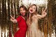 Portrait of two excited cheery women in sparkly dresses