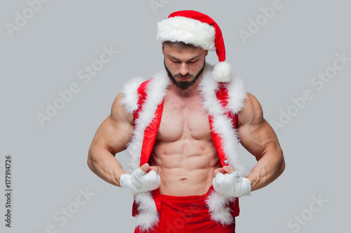 Plakat Boże Narodzenie. Sexy Święty Mikołaj. Młody mięśniowy mężczyzna jest ubranym Święty Mikołaj kapelusz demonstruje jego mięśnie. Muscular Fighter kickbox Z białymi bandaże.
