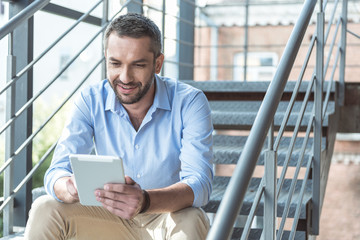 Wall Mural - Joyful attractive bristled guy is enjoying his device outdoors