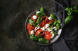 Italian caprese salad with sliced tomatoes, mozzarella cheese, basil, olive oil. Served in vintage metal plate on textile napkin over dark metal background. Top view with space. Rustic style