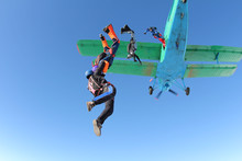 Skydivers Are Jumping Out Of A Biplane.