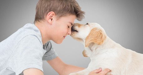 Poster - Boy against grey background with friendly dog licking his face