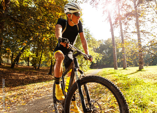 Plakat Młody cyklista odpoczywa po tym jak jadący rower górskiego przy lasem. Zmierzch.