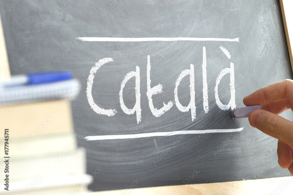Hand writing on a blackboard in a language class with the word CATALAN wrote on. Some books and school materials. - obrazy, fototapety, plakaty 