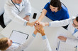 © Syda Productions - group of doctors making high five at table