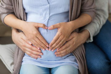 close up of pregnant woman making hand heart