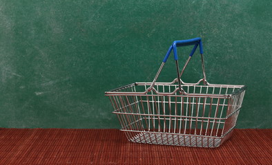 Shopping basket on desk, chalkboard background