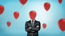 A Businessman In Front View With Crossed Arms Stands Surrounded By Many Red Party Balloons With One Hiding His Face.
