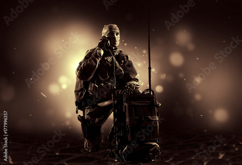 The soldier of the special unit in military uniform sits near the satellite communications apparatus and causes support плакат