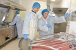 Factory workers overseeing mixing of ingredients in vat