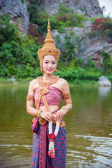 Wall Mural - Beautiful asian woman wearing Thai ancient traditional costume dancing and smiles near by the river