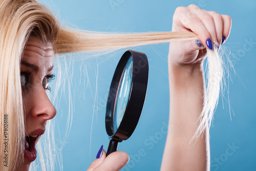 Zdjęcie XXL Kobieta patrzeje włosy przez powiększać - szkło