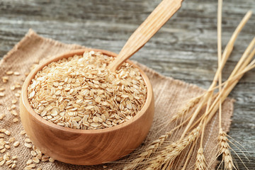 Bowl with oatmeal flakes on wooden background