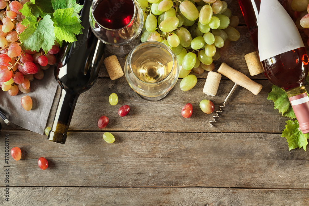 Composition with wine and grapes on wooden background