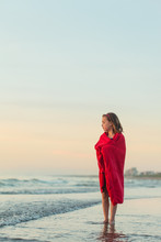 Little Girl Wrapped In Red Towel Standing In The Ocean