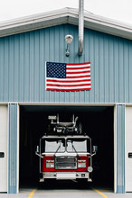 Fire Truck Parked In Firehouse With American Flag