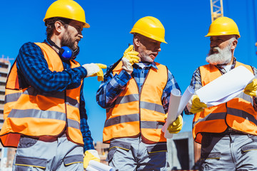 Wall Mural - Three workers in uniform at construction site