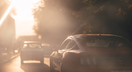 the red sports car is stopped at the traffic lights. the hand of the driver wearing the watch, hang on window of the car