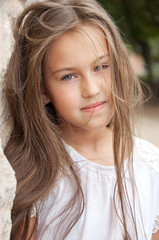 Beautiful school girl with long hair in the park.  Prety Girl with a model appearance and with fashionable poses. Child of 8 years.