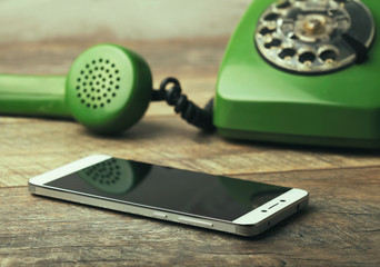 old green vintage telephone vs modern mobile phone show evolution in telecommunications.