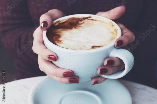 Plakat Puchar porannej kawy z mlekiem pianką w ręce kobiety