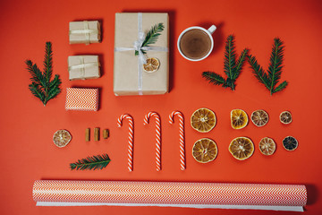 Wall Mural - Christmas concept. Hot chocolate with fir tree, gift, candy canes on red board. Top view with copy space