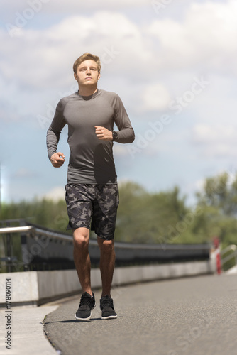 Plakat Młody jogging mężczyzna w mieście w sportswear w popielatym koloru bieg w miastowym miejscu, miasto słoneczny dzień.