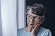 Elderly woman looking through window