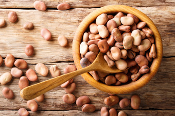 Wall Mural - Organic broad beans close-up in a wooden bowl on a table. horizontal top view