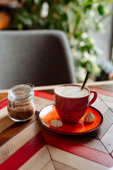 Wall Mural - red cup of cappuccino with latte art on old multi-colored rustic table