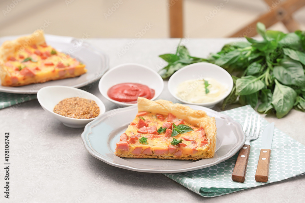 Plate with slice of delicious sausage casserole on table