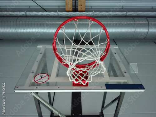 Plakat Widok z dołu od boiska do koszykówki, przez obręcz do koszykówki, do oświetlonego sufitu hali sportowej